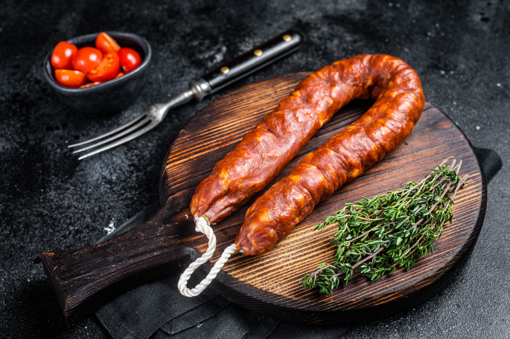 Traditional spanish Chorizo sausage, dry cured pork meat. Black background. Top view